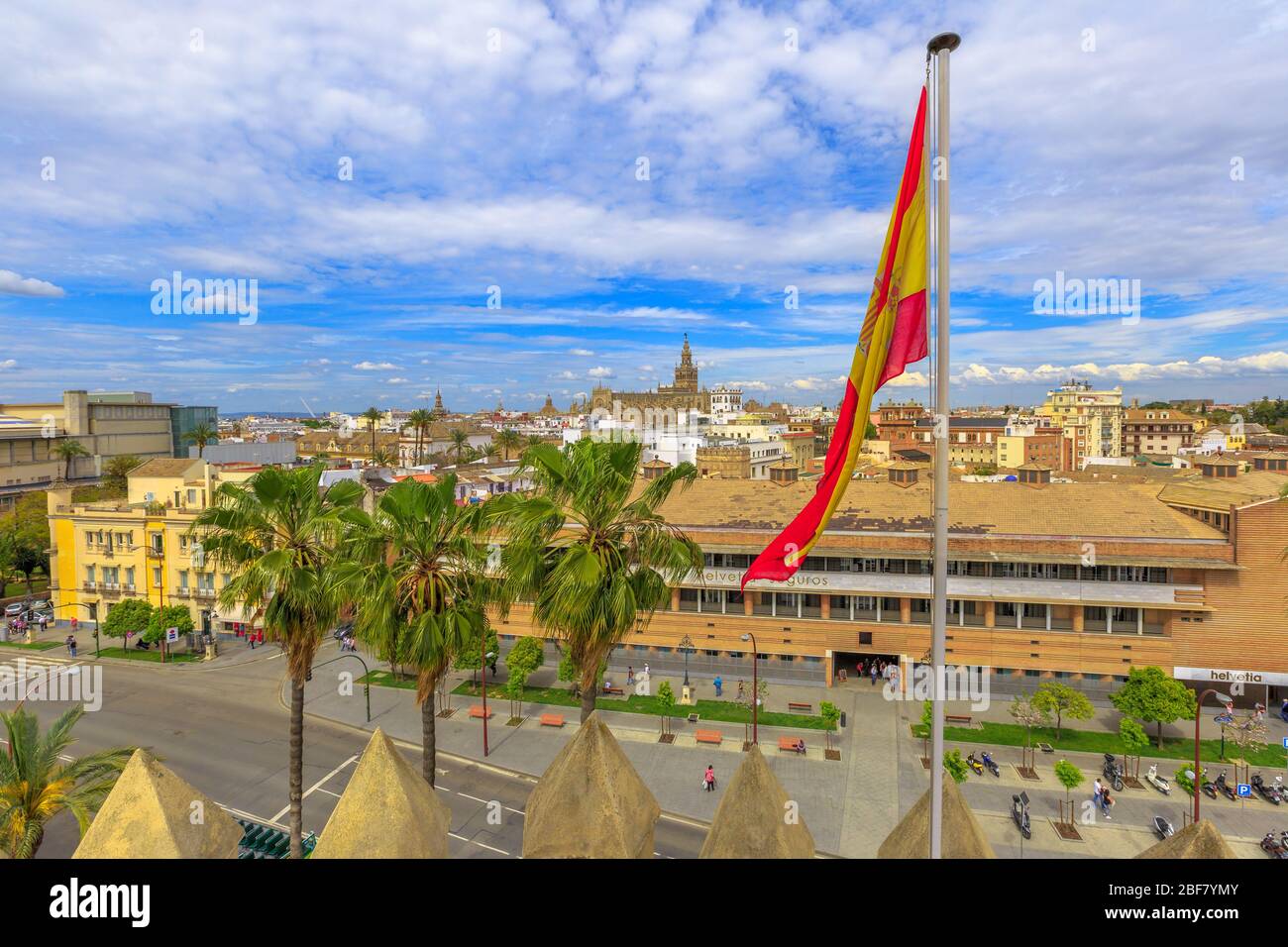 Vista aerea dello skyline di Siviglia con bandiera spagnola dalla Torre d'Oro o Torre del Oro. In lontananza, la famosa Cattedrale di Santa Maria del Foto Stock