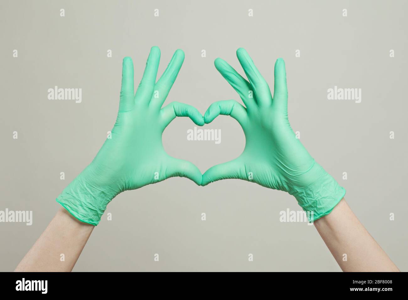Guanti per uso medico sulle mani. Il cuore del medico passa in guanti medici su sfondo bianco Foto Stock