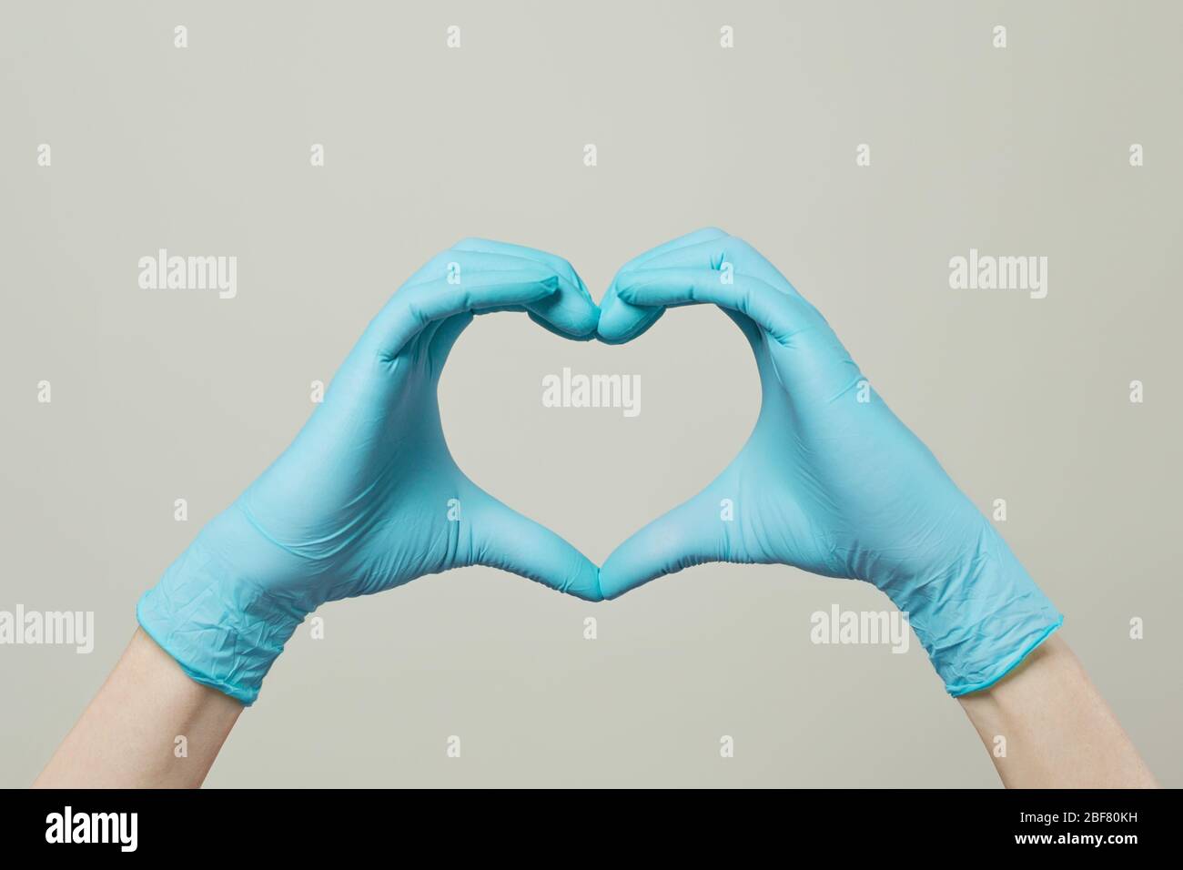 Cuore da mani del medico in guanti medici su sfondo bianco Foto Stock