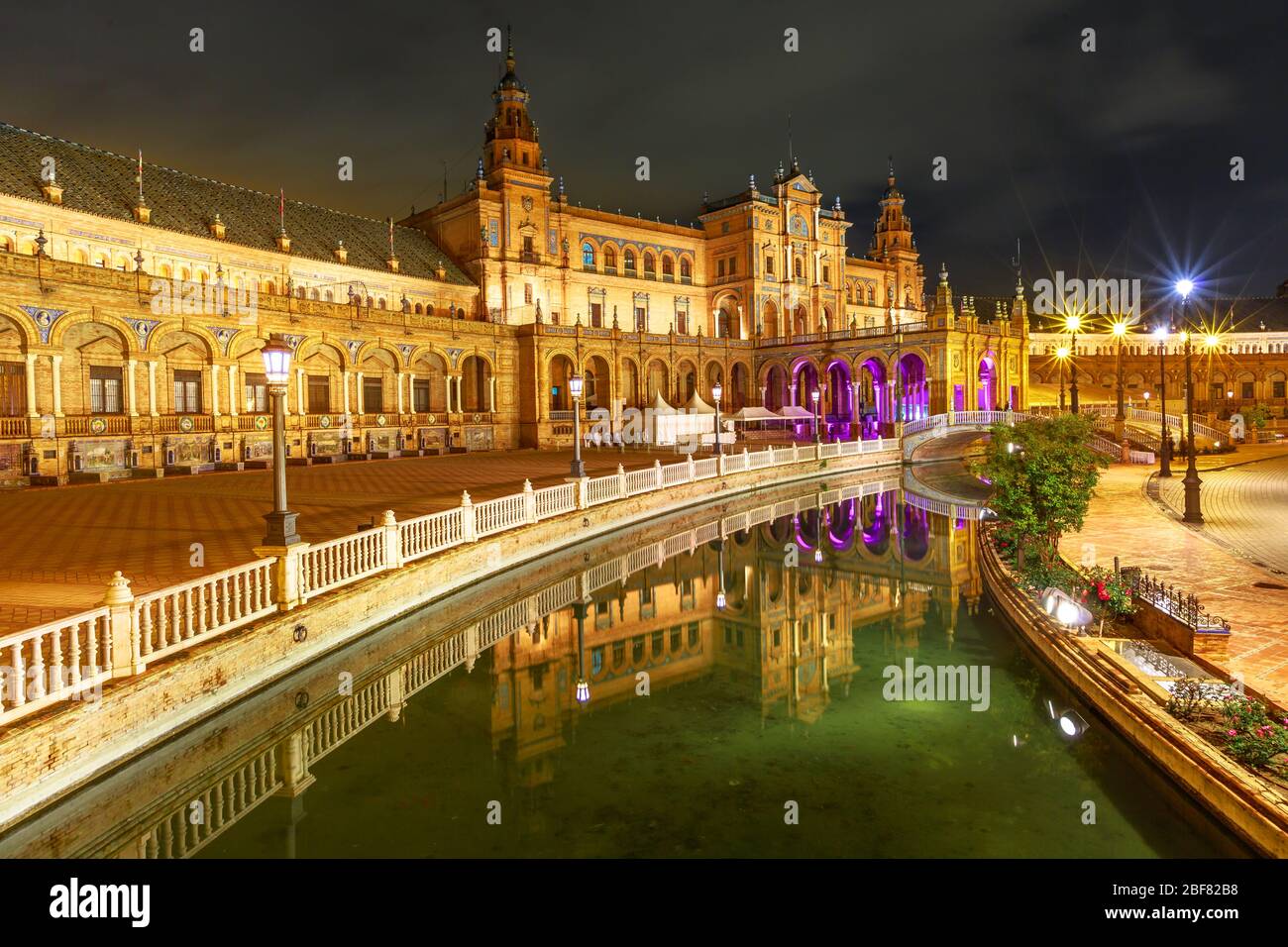 Edificio rinascimentale in Plaza de Espana a Siviglia, Andalusia, Spagna, si riflette sul canale del fiume Guadalquivir. Panoramica Piazza Spagna illuminata a. Foto Stock