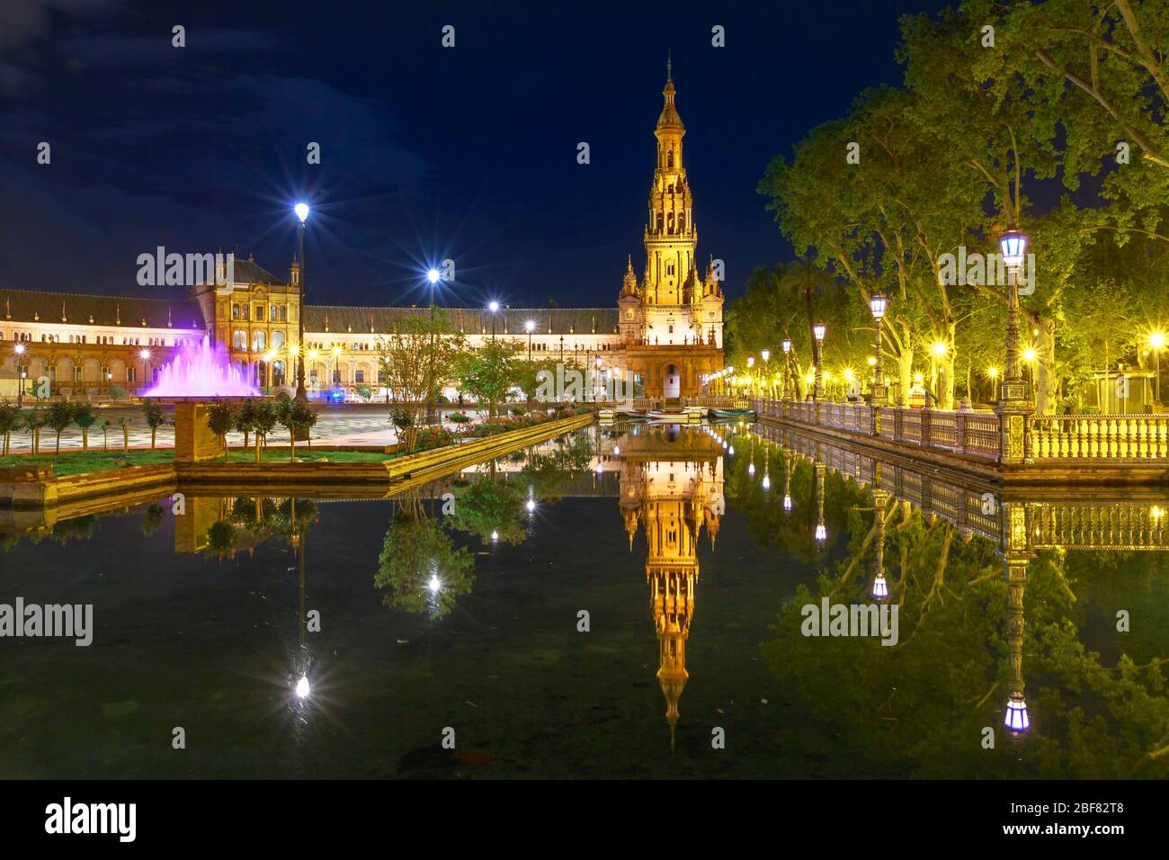 Panorama panoramico di Piazza Spagna in Andalusia, Spagna, illuminato di notte. Edificio rinascimentale e una delle due torri in Plaza de Espana si riflette Foto Stock