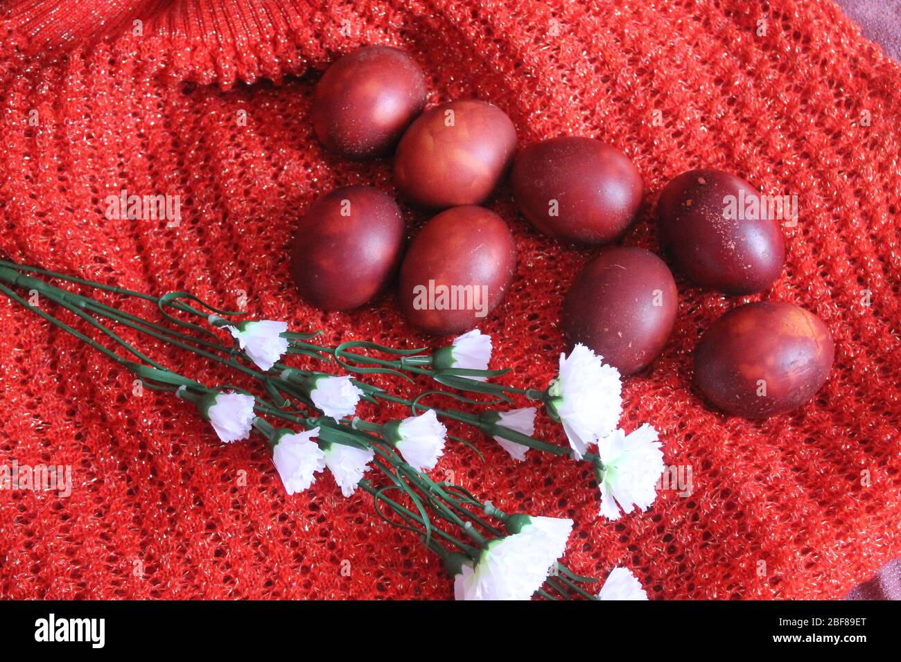 Uova dipinte di rosso con fiori e candele per la festa di Pasqua Foto Stock