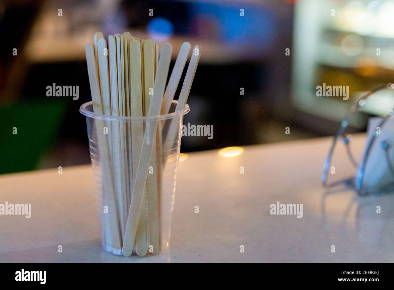 Bastoncini di legno in tazza di plastica per mescolare lo zucchero nel caffè in caffetteria. Foto Stock
