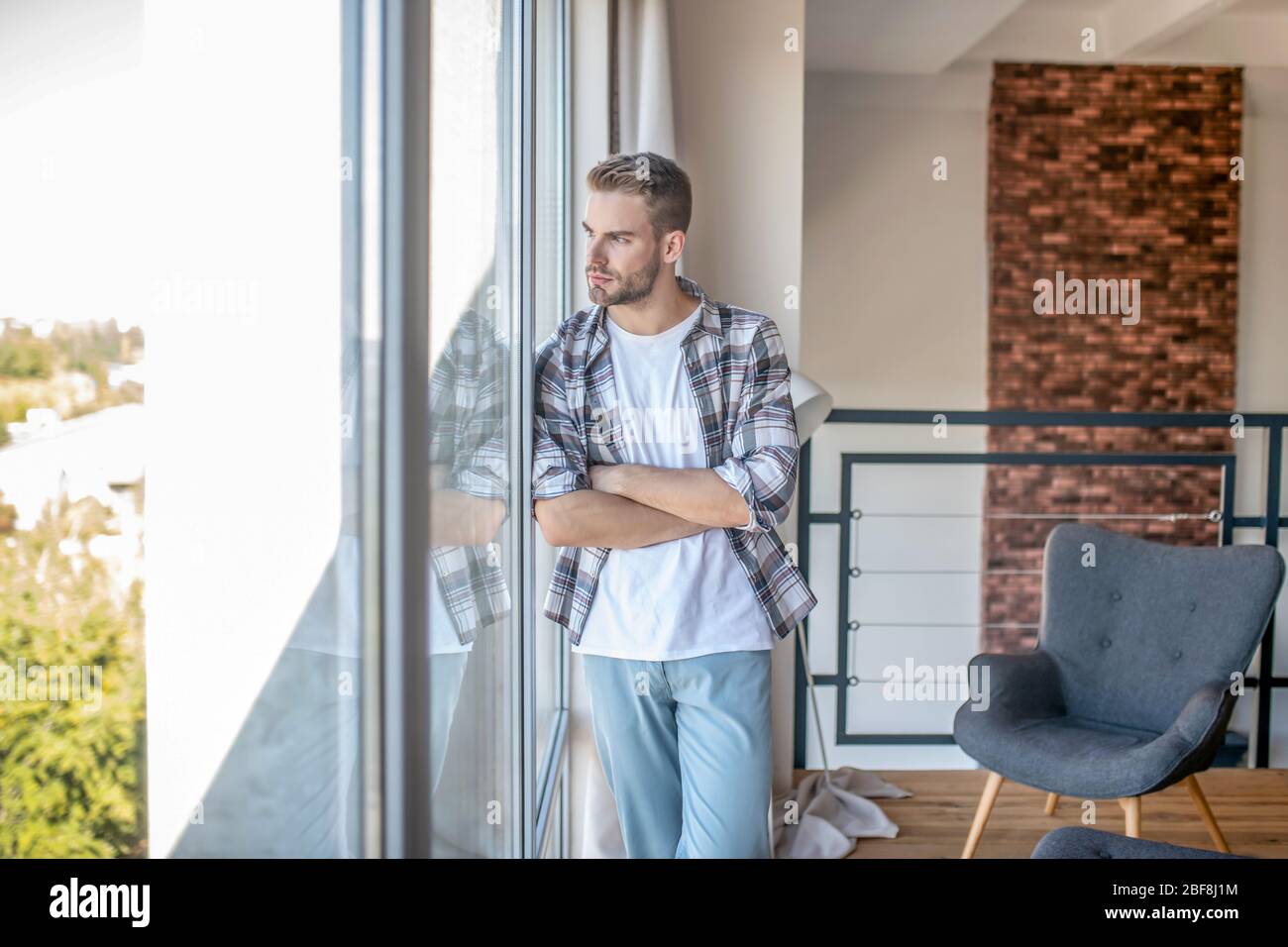Giovane uomo in una camicia a scacchi che guarda pensieroso Foto Stock