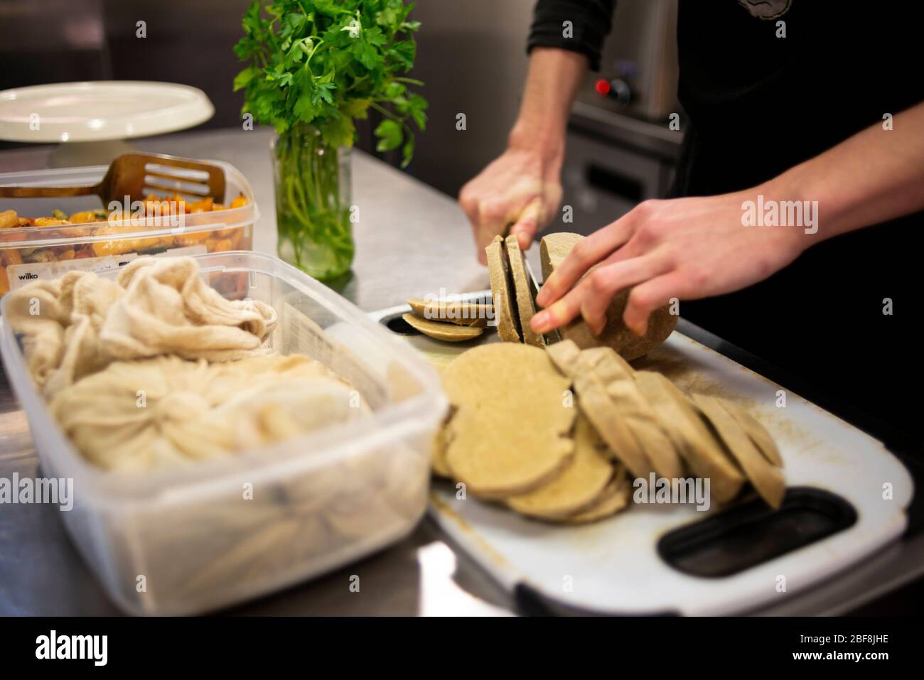 Seitan fatto in casa viene tagliato in preparazione per preparare piatti vegani e vegetariani in una cucina professionale Foto Stock