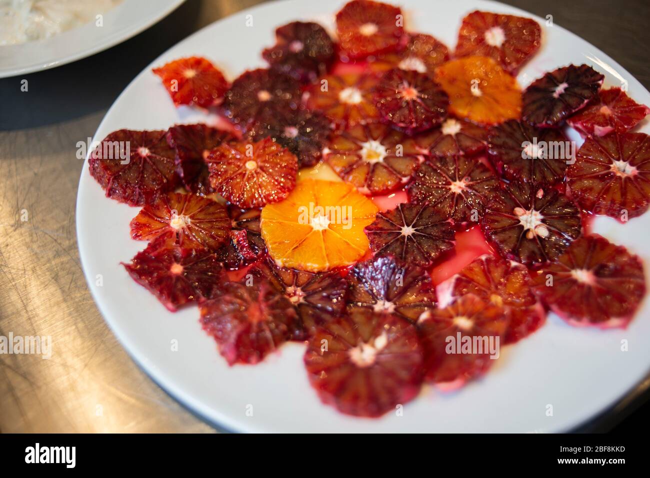 Un grande piatto bianco coperto da fette di arance di sangue Foto Stock