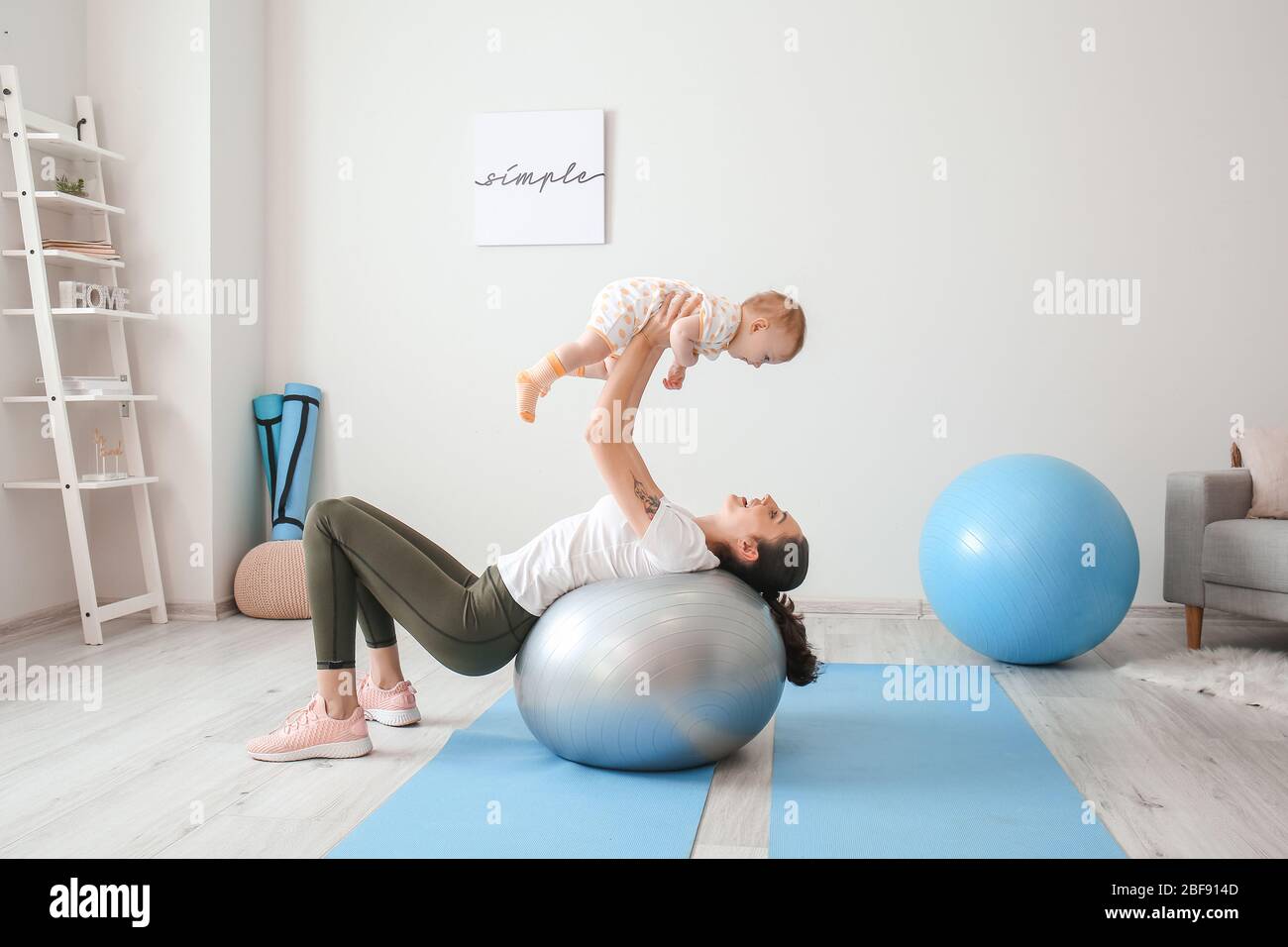 Giovane madre sportiva e il suo bambino che fa esercizi con il fitness a casa Foto Stock