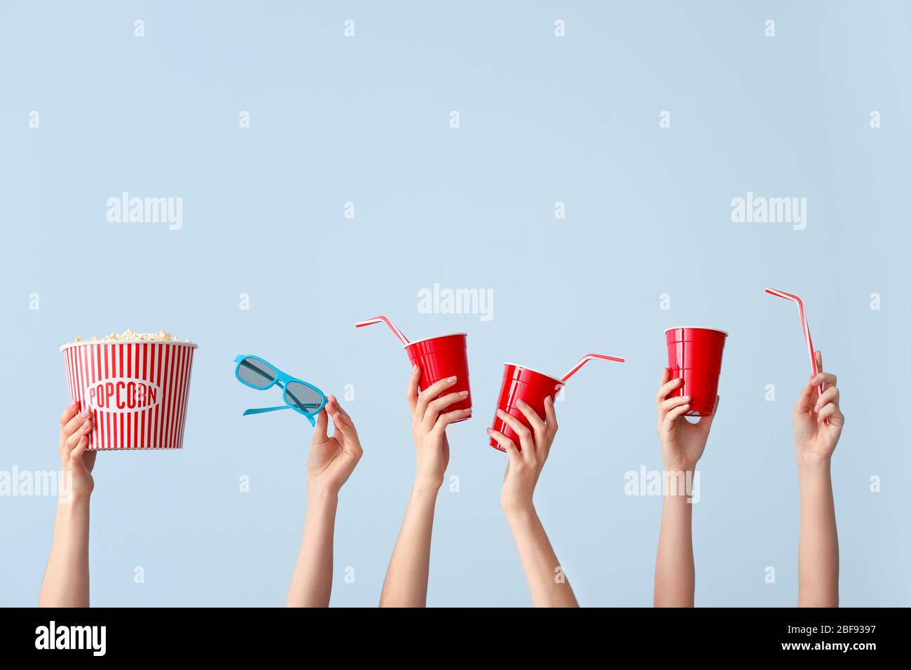 Molte mani con popcorn, bevanda e occhiali su sfondo colore Foto Stock