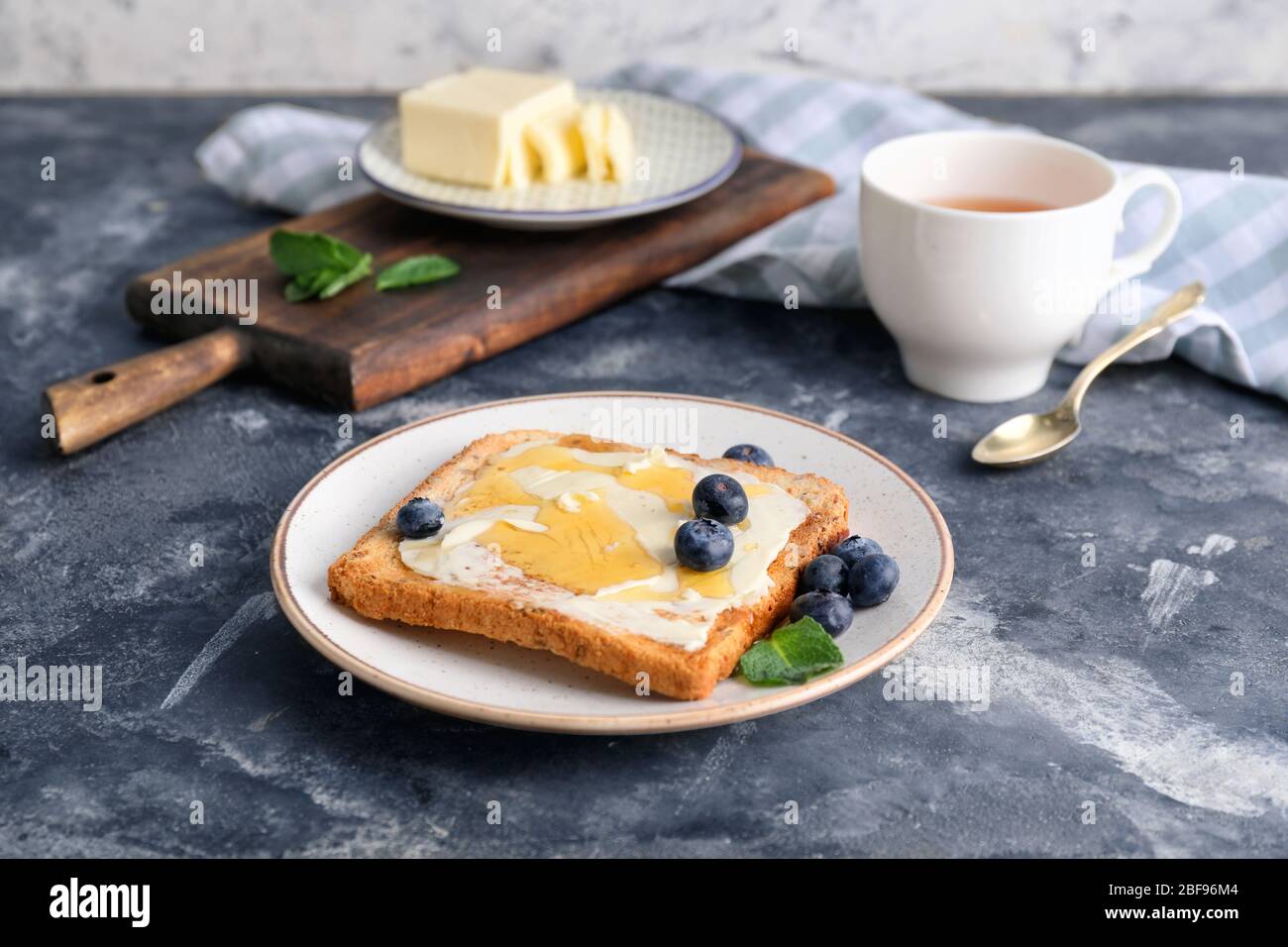 Gustoso pane tostato con miele, burro e frutti di bosco a tavola Foto Stock