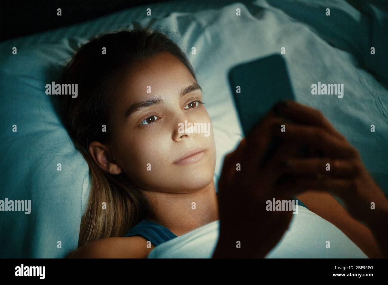 Giovane womanl bello a letto utilizzando il telefono cellulare a tarda notte in camera da letto buio, Internet dipendenza concetto Foto Stock