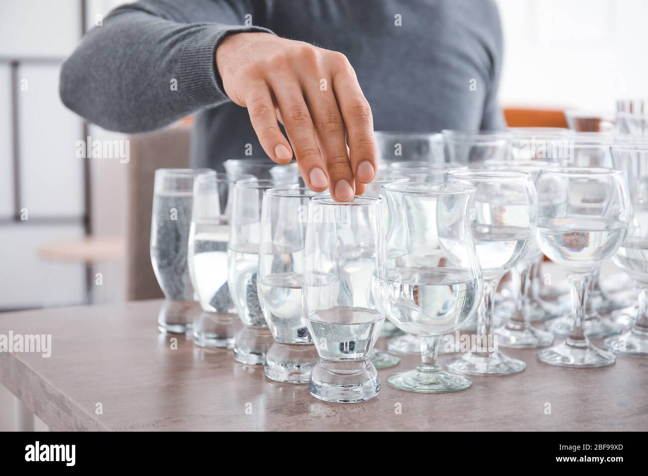 Giovane uomo che suona musica su bicchieri con acqua a casa, primo piano  Foto stock - Alamy