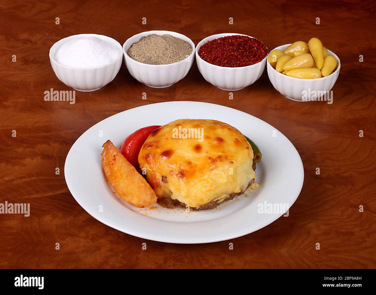 molto bella hasanpasa pataties con purè di patate, purè di peperoni, piatto bianco sul tavolo di legno, insieme alla fragrante spezia turca Foto Stock