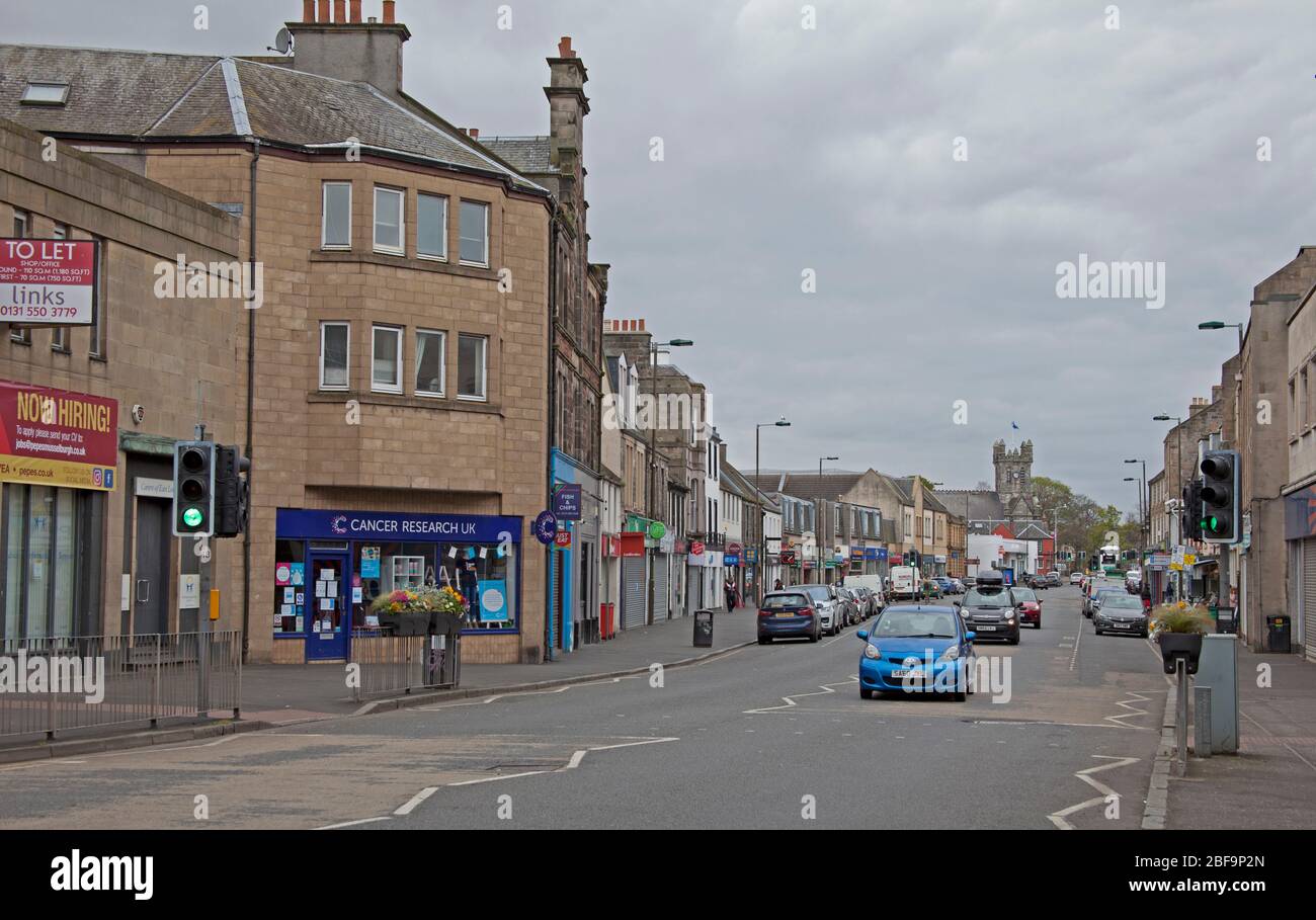 Musselburgh, High Street, East Lothian, Scozia, Regno Unito. La strada principale, normalmente trafficata, in tempi normali mostra pavimenti molto tranquilli a causa del Coronavirus Lockdown ma diverse auto che passano attraverso. Foto Stock