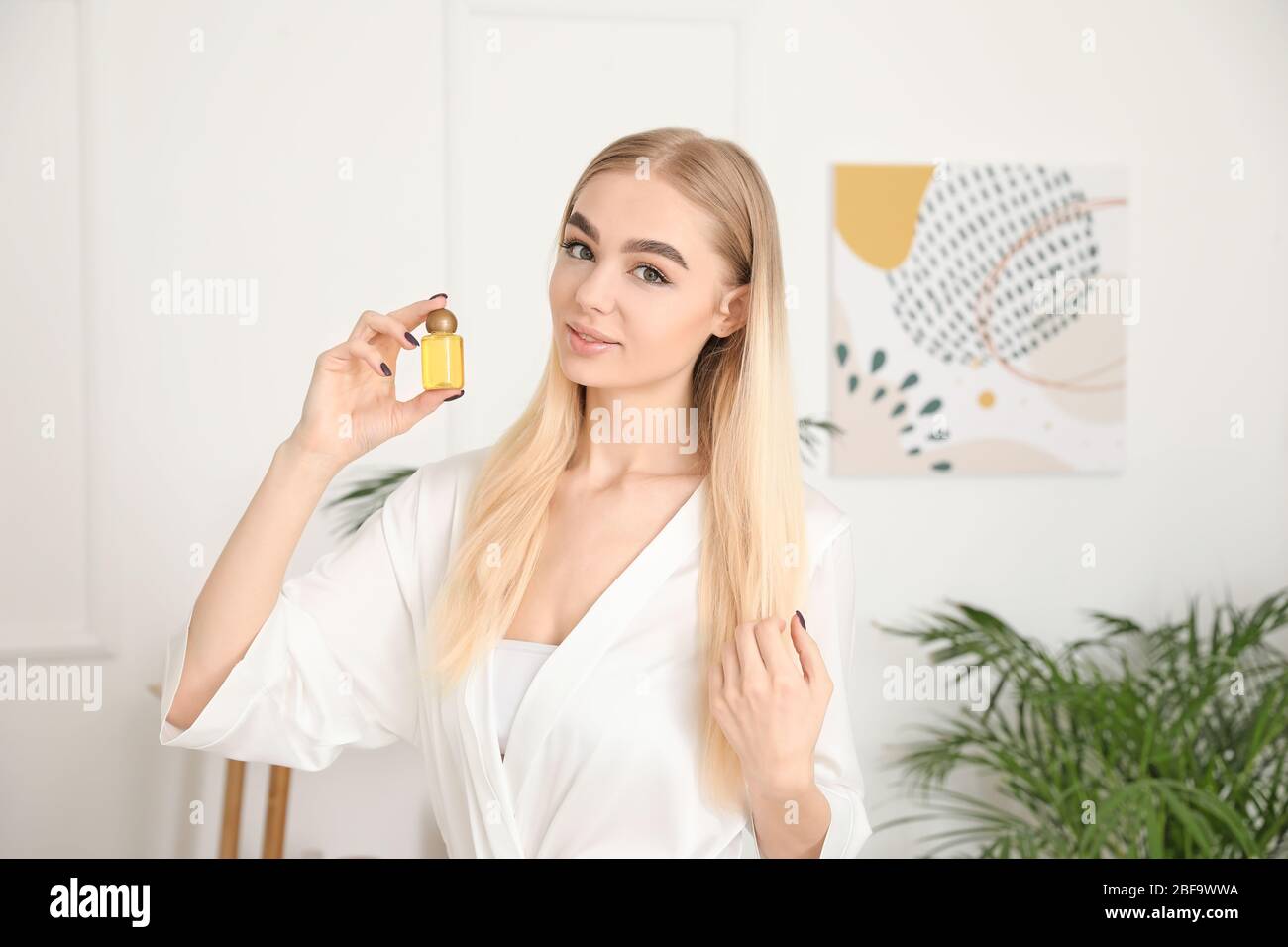 Bella giovane donna con bottiglia di olio in bagno Foto Stock