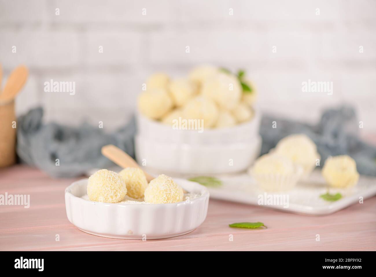 Caramelle fatte in casa con mandorle arrosto al cocco su un tavolo di legno rosa. Foto Stock