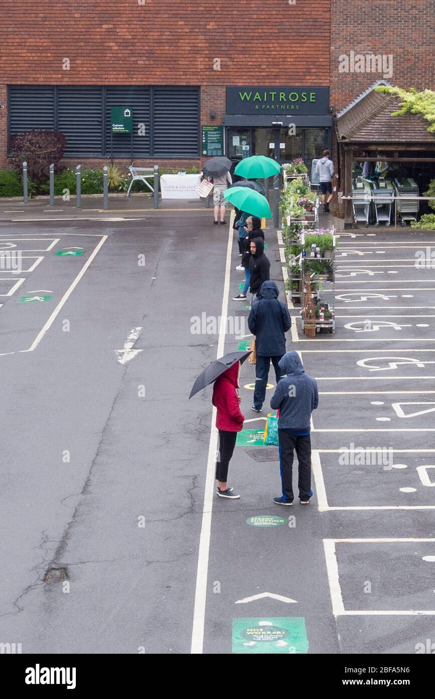 Londra, Regno Unito. 17 aprile 2020. I clienti che si trovano nella coda della pioggia nel parcheggio in attesa di entrare in un supermercato Waitrose nel nord-ovest di Londra durante il blocco della pandemia di coronavirus. La catena di supermercati, insieme ad altri supermercati, ha implementato un sistema di ingresso controllato in questo negozio che mantiene i clienti a 2 metri di distanza, limita le scorte e garantisce che le scorte sugli scaffali rimangano disponibili per tutti i clienti. Credit: Stephen Chung / Alamy Live News Foto Stock