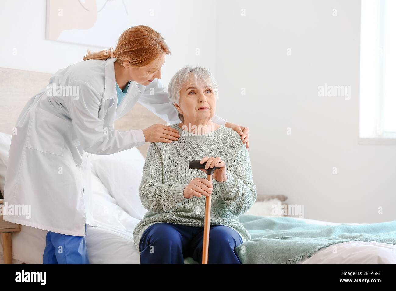 Donna anziana con disabilità mentale e medico a casa Foto Stock