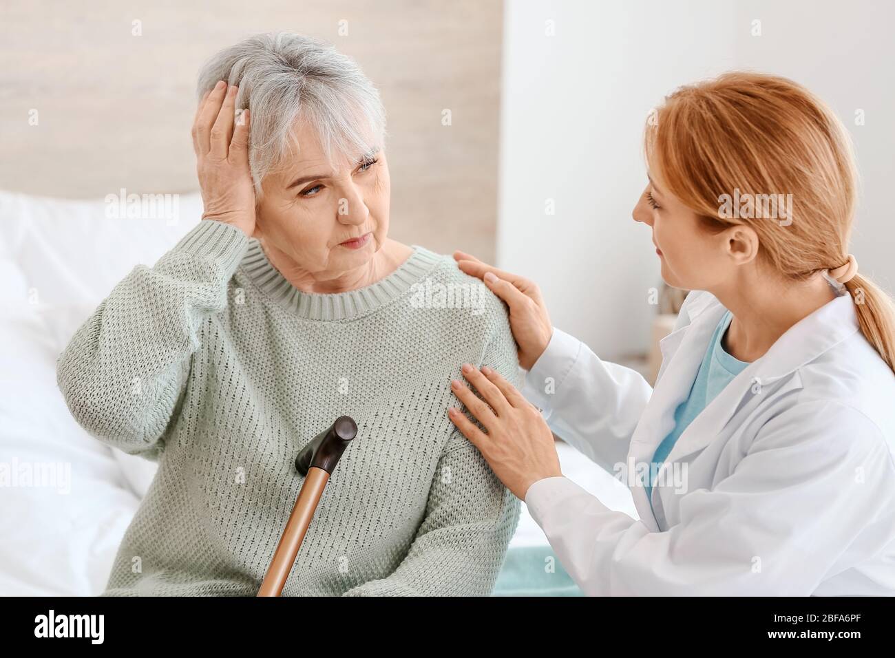Donna anziana con disabilità mentale e medico a casa Foto Stock