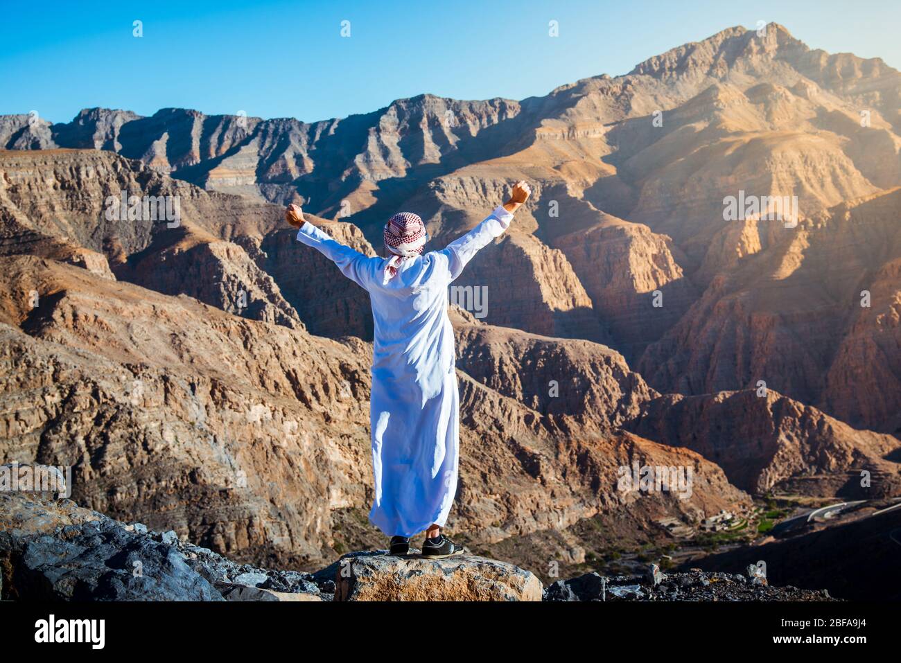 Uomo arabo che gode della vista sul deserto Jebel Jais montagna di arenaria in Ras al Khaimah Emirati Arabi Uniti Foto Stock