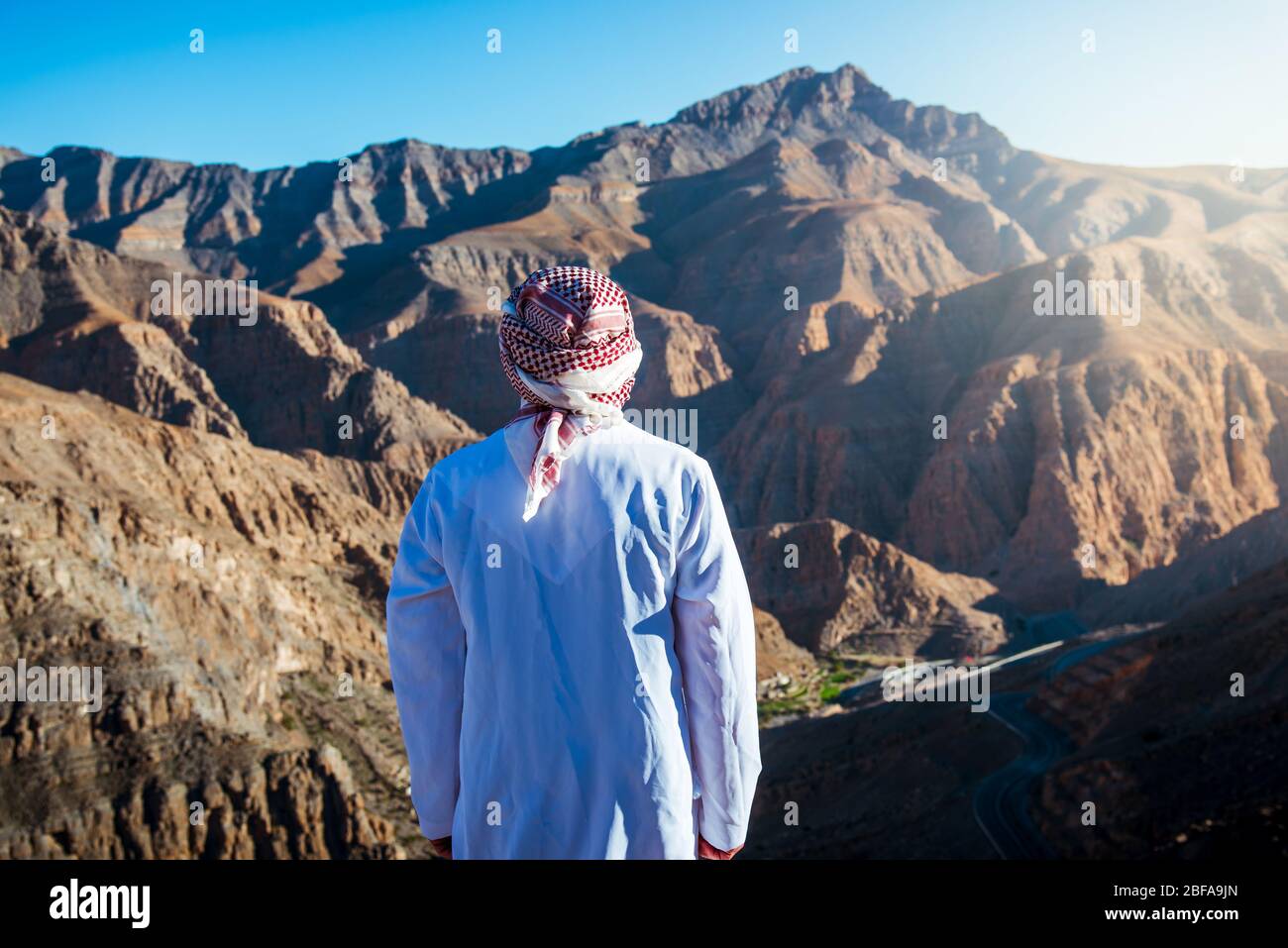 Uomo arabo che gode della vista sul deserto Jebel Jais montagna di arenaria in Ras al Khaimah Emirati Arabi Uniti Foto Stock