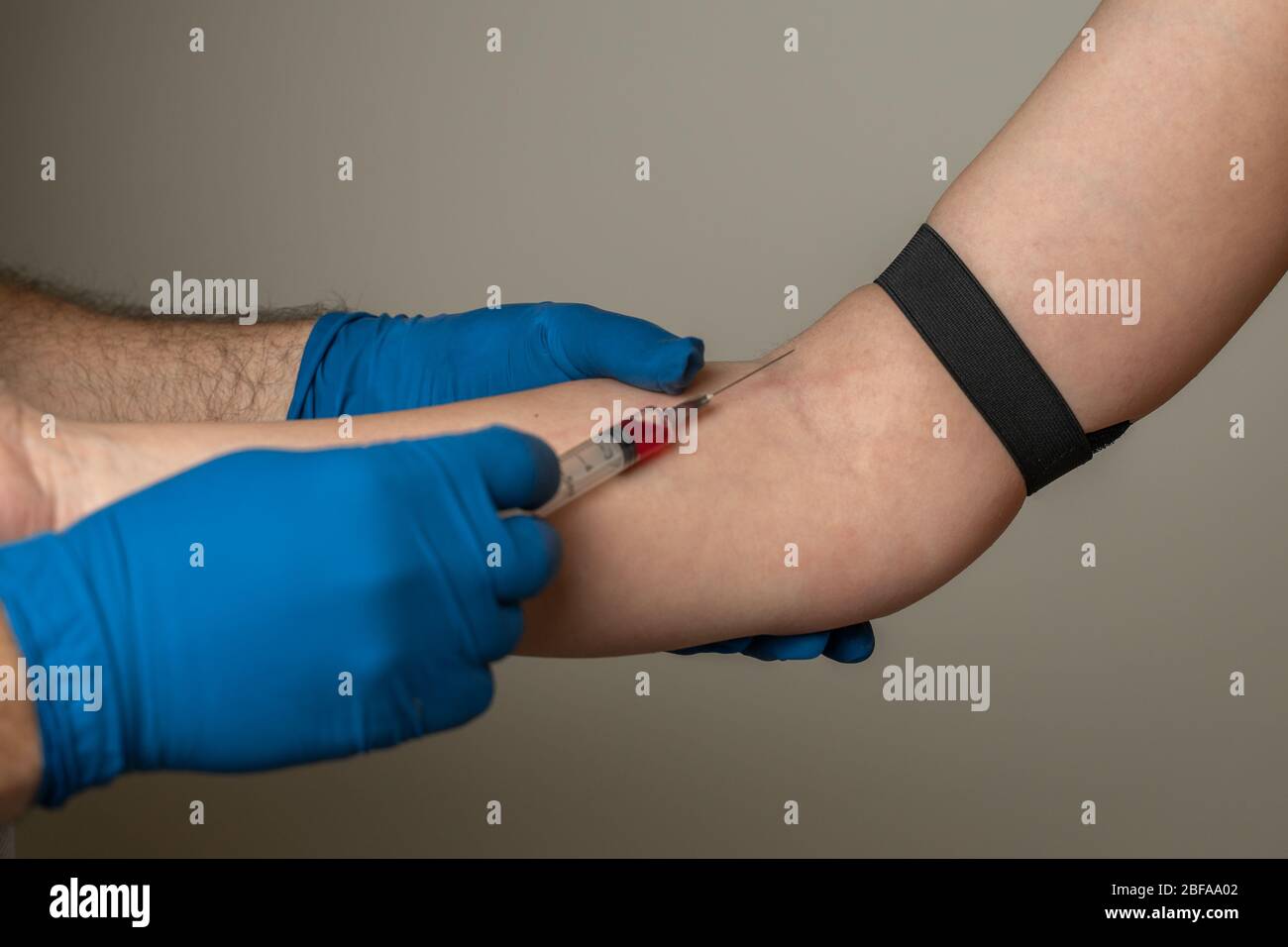 un medico che utilizza guanti monouso preleva il sangue dalla vena del paziente per l'analisi Foto Stock