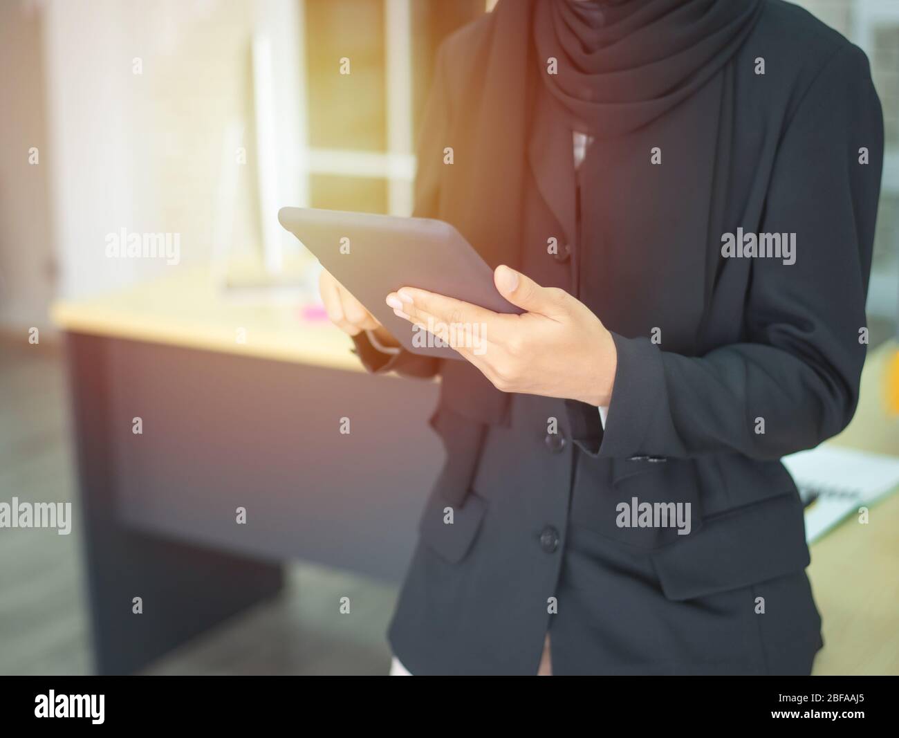 Giovane donna d'affari musulmana asiatica che usa un tablet grafico mentre lavora con il computer in studio o in ufficio. Foto Stock