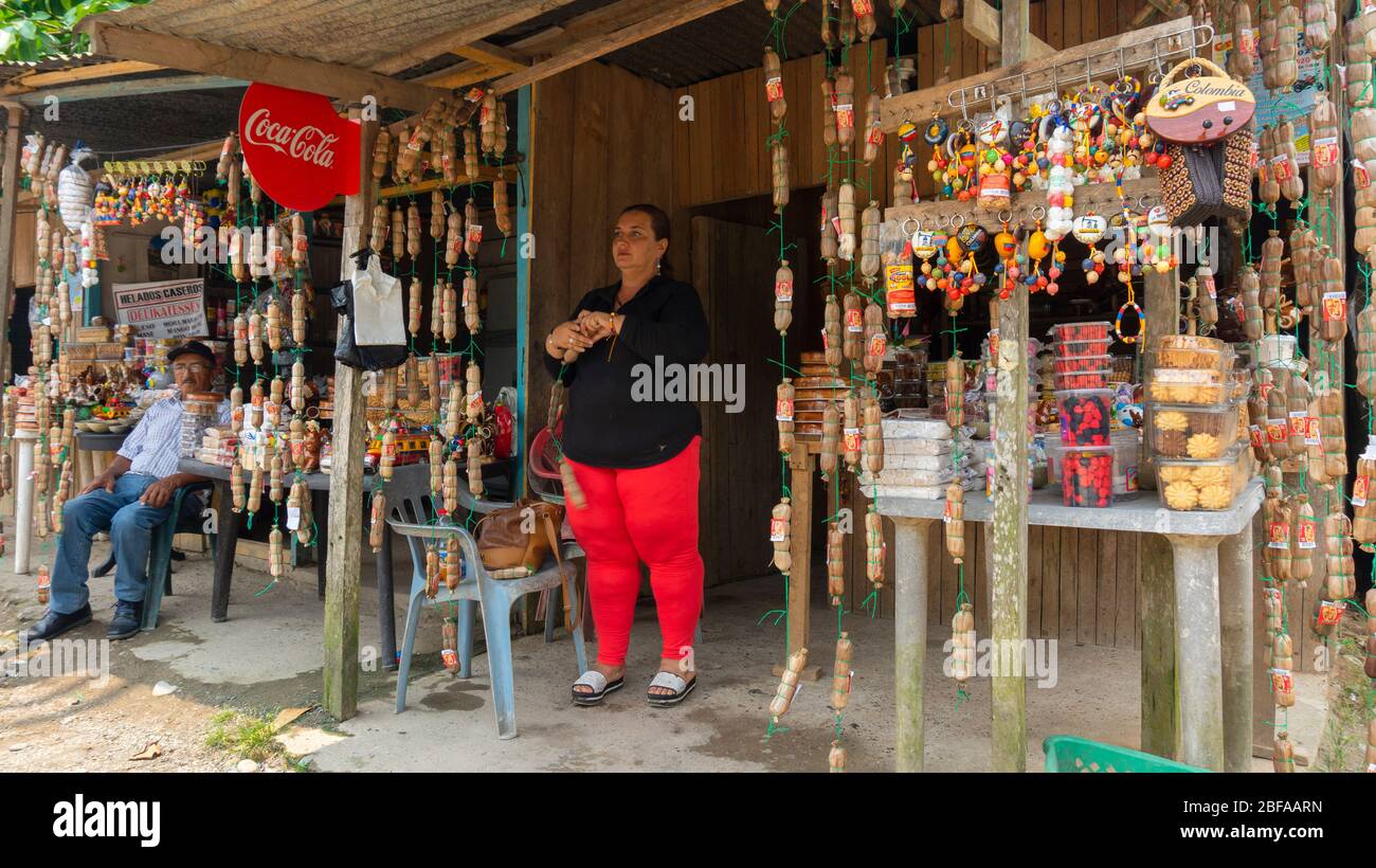 La Dorada, Putumayo / Colombia - Marzo 8 2020: Donna in piedi alla porta del suo negozio tradizionale di artigianato colombiano e dolci sulla strada Foto Stock