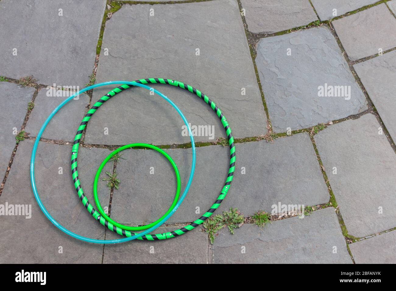 tre tipi di esercizi disposti su uno sfondo flagstone. Un cerchio fitness, un cerchio da ballo e un mini-cerchio. Con spazio di copia Foto Stock