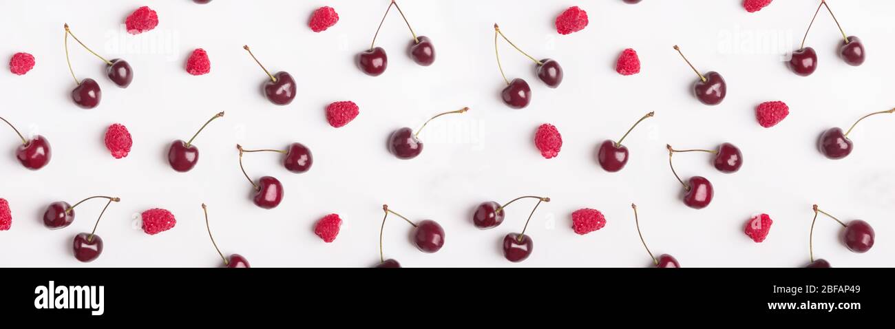 Lotto di ciliegia fresca e lampone crudo mature sparse su sfondo bianco. Foto Stock