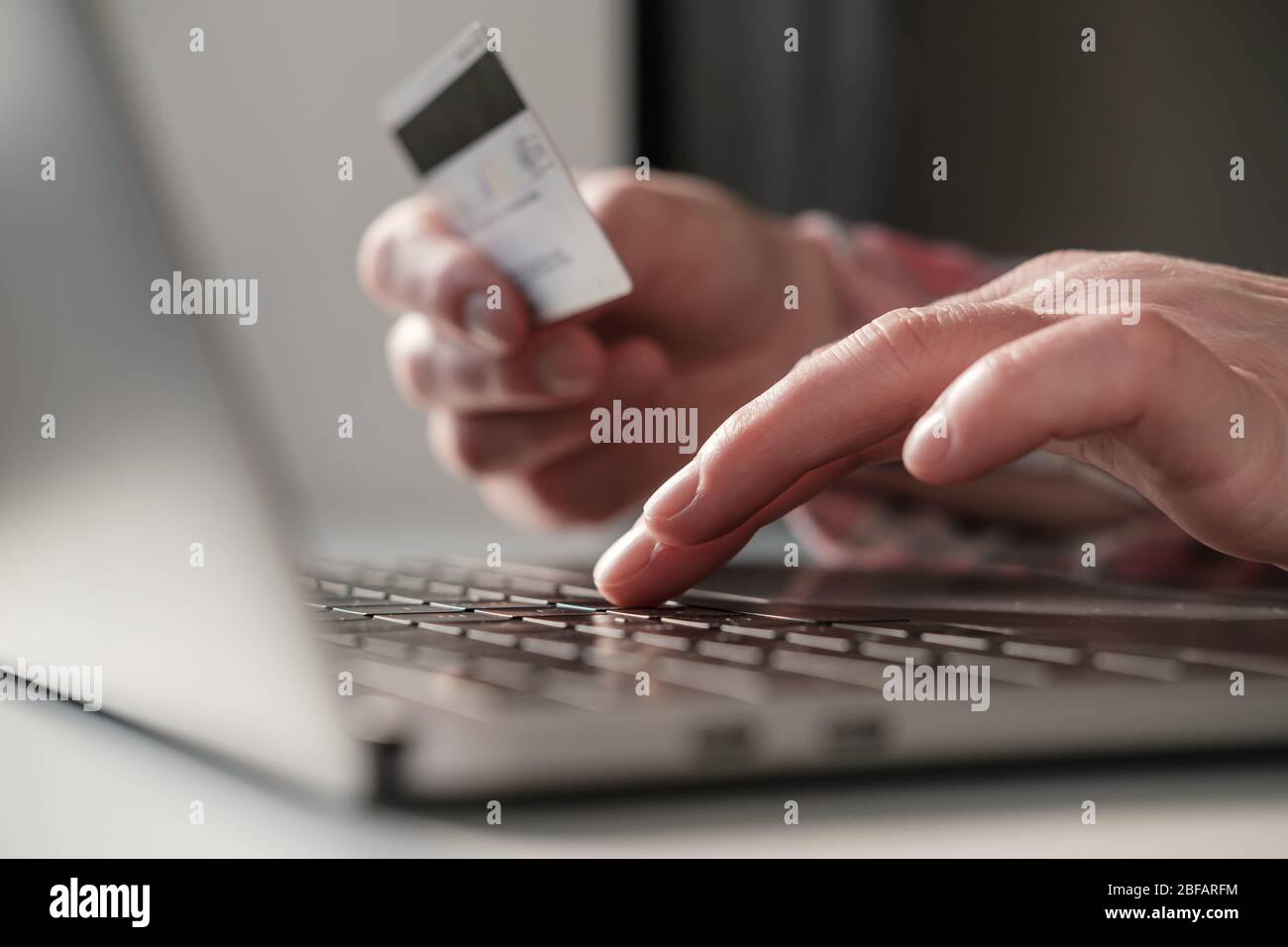 Le mani femminili immettono i dati bancari di una carta di credito su un computer portatile per pagare gli acquisti online. Concetto di autoisolamento dovuto ad un'epidemia di virus. Moderno Foto Stock
