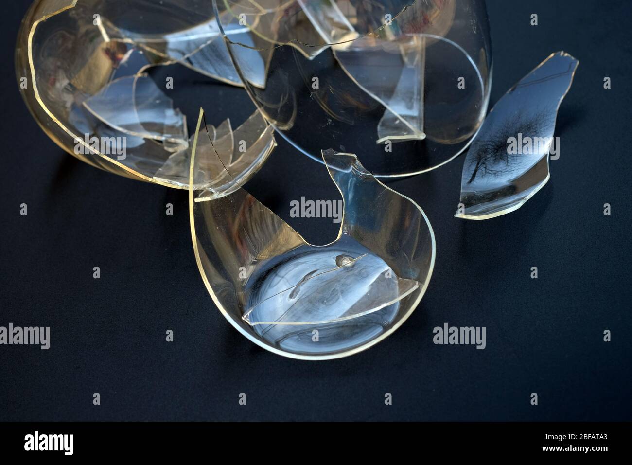 Tazza rotta su sfondo nero. Tazza con doppio fondo trasparente. Vetro frantumato dagli utensili da cucina. Pericolo di taglio dei taglienti. Foto Stock