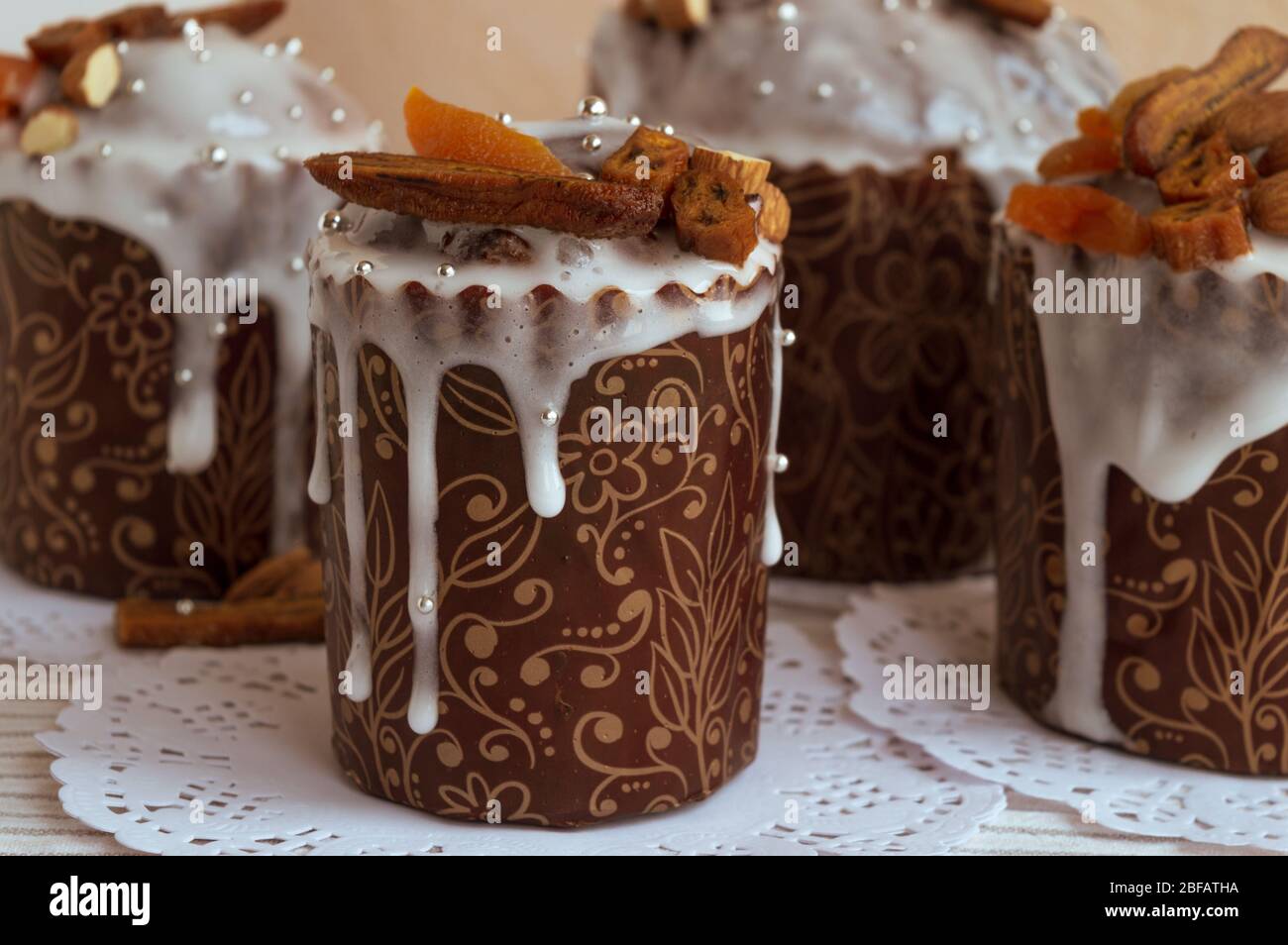Quattro deliziose torte pasquali fatte in casa insieme ai tovaglioli decorate con banane secche, albicocche d'arancia, mandorle e piccola elegante perla d'argento zucchero Foto Stock