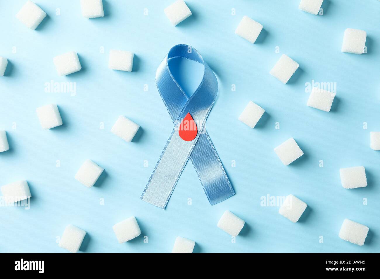 Nastro di sensibilizzazione sul diabete e cubetti di zucchero su sfondo blu Foto Stock