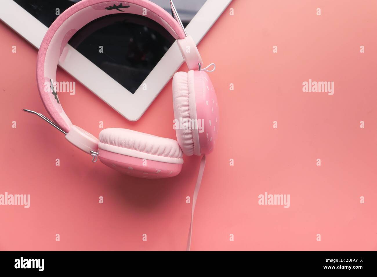 cuffie e tablet digitali su sfondo rosa. Foto Stock
