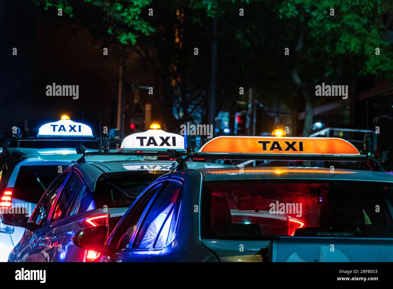 Taxi in fila con il loro cartello taxi sul tetto illuminato di notte a Sydney, Australia Foto Stock