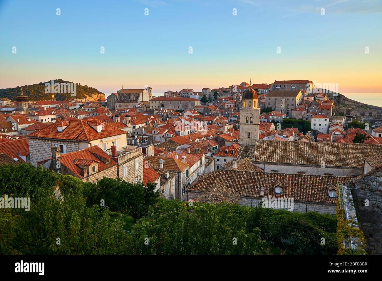 Vista al tramonto sui tetti in piastrelle di argilla della città vecchia di Dubrovnik, Croazia, con il Mar Mediterraneo sullo sfondo Foto Stock