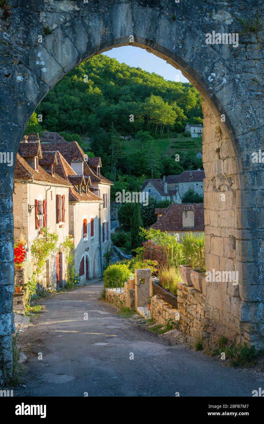 Impostando la luce del sole sulle case al varco di ingresso a Saint-Cirq-Lapopie, Valle del Lot, Occitanie, Francia Foto Stock