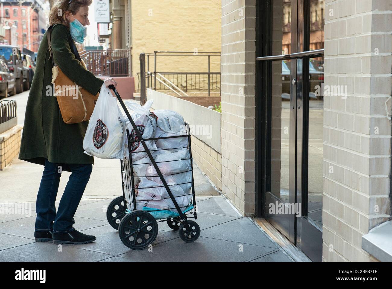 Una donna che viene a casa con i suoi generi alimentari a New York City, durante la pandemia COVID19. Le distanze sociali avevano avuto effetto e le persone si stavano caricando Foto Stock