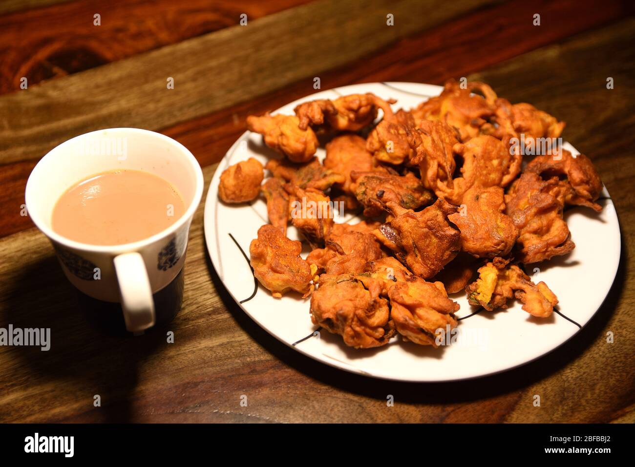 Chai con pakora e bhajiya e servito su piatto su sfondo di legno Foto Stock