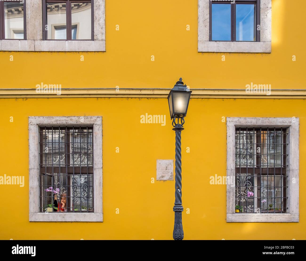 Budapest, Ungheria, marzo 2020, vecchia donna che guarda una strada da una finestra durante il periodo di confinamento da un edificio nel distretto del Castello di Buda Foto Stock