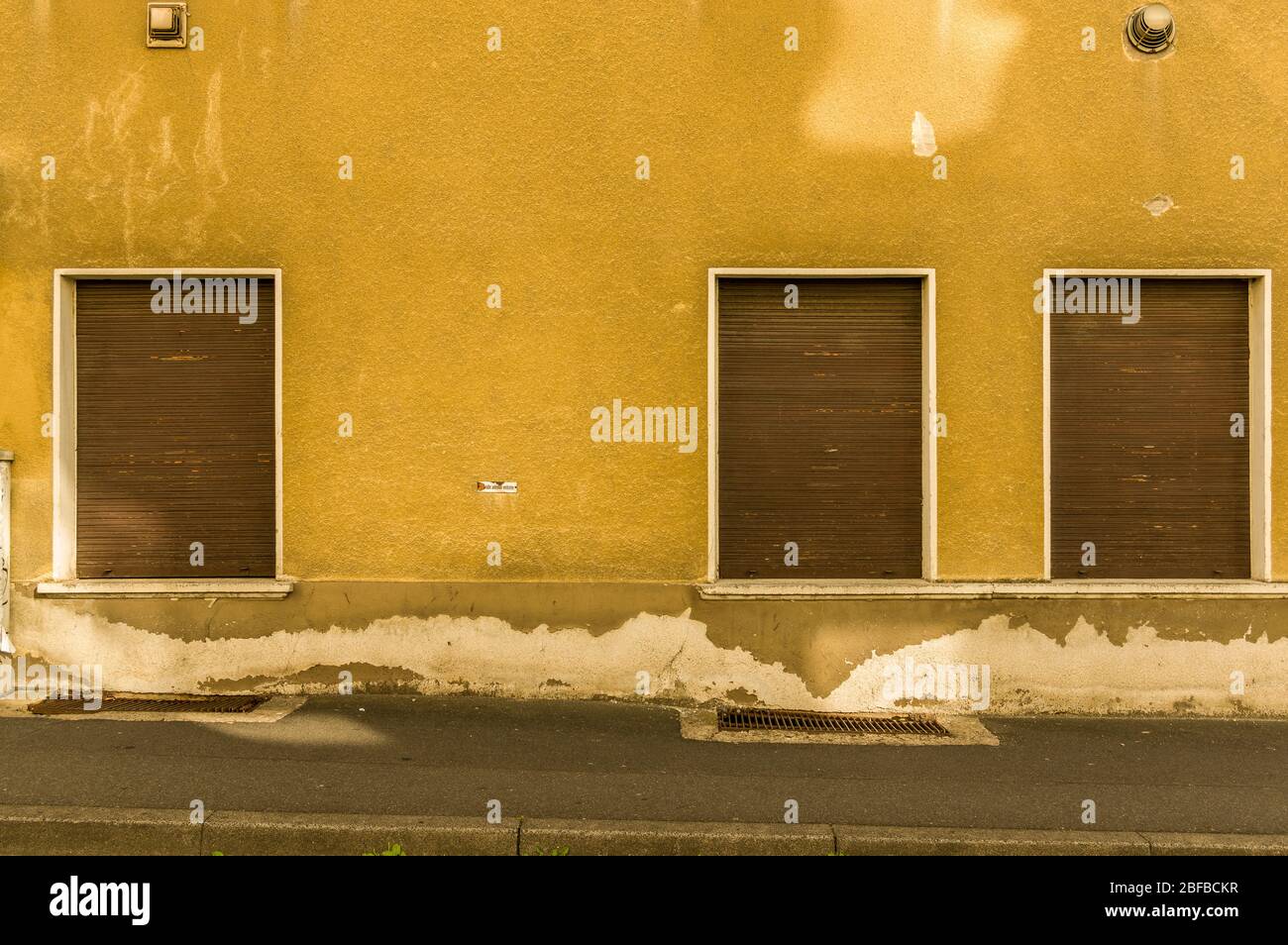 facciata vecchia con 3 persiane di legno marrone di una casa con marciapiede Foto Stock