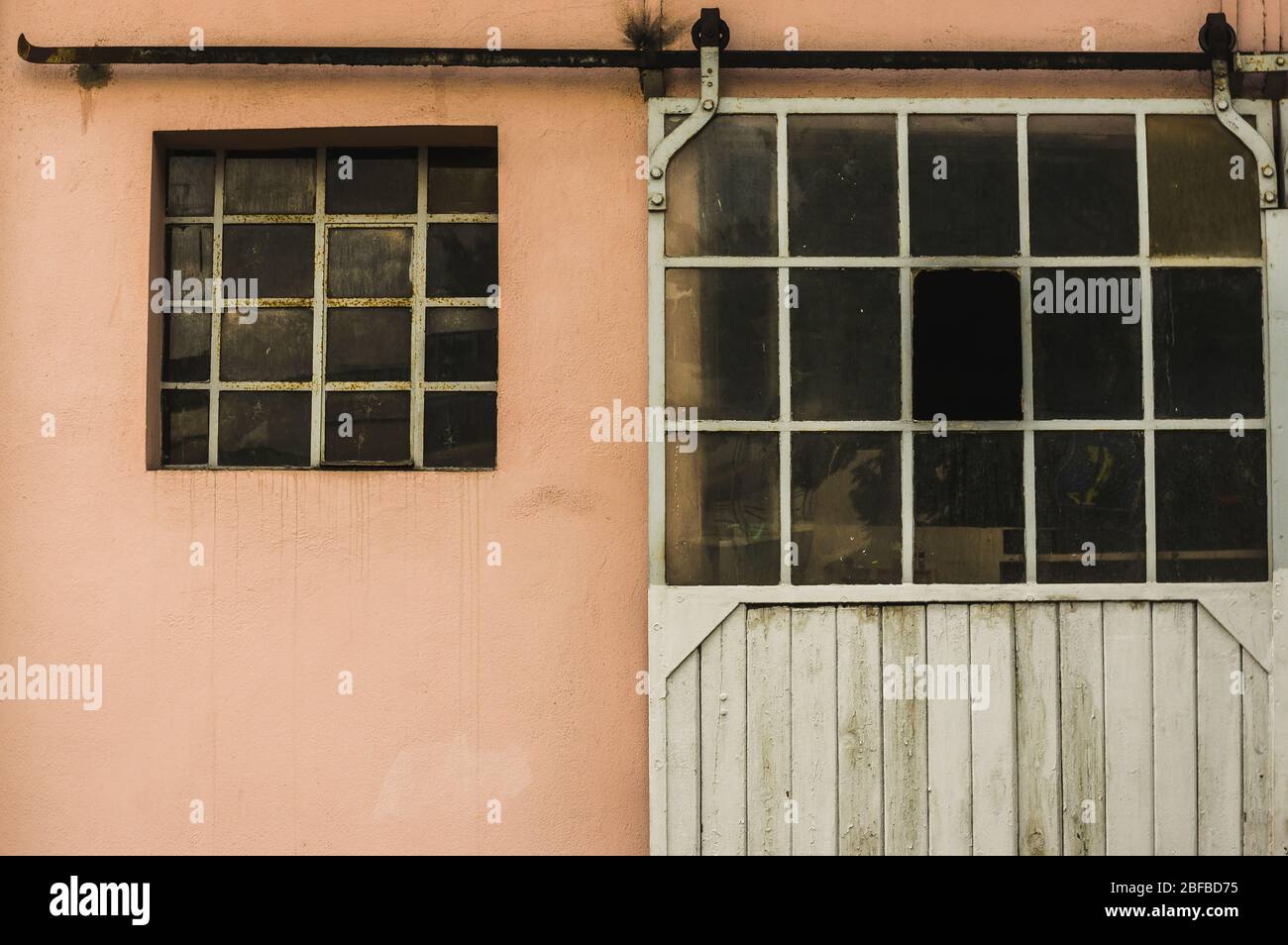 Facciata di un vecchio edificio con finestre in metallo e rungs porta di rotolamento bar Foto Stock