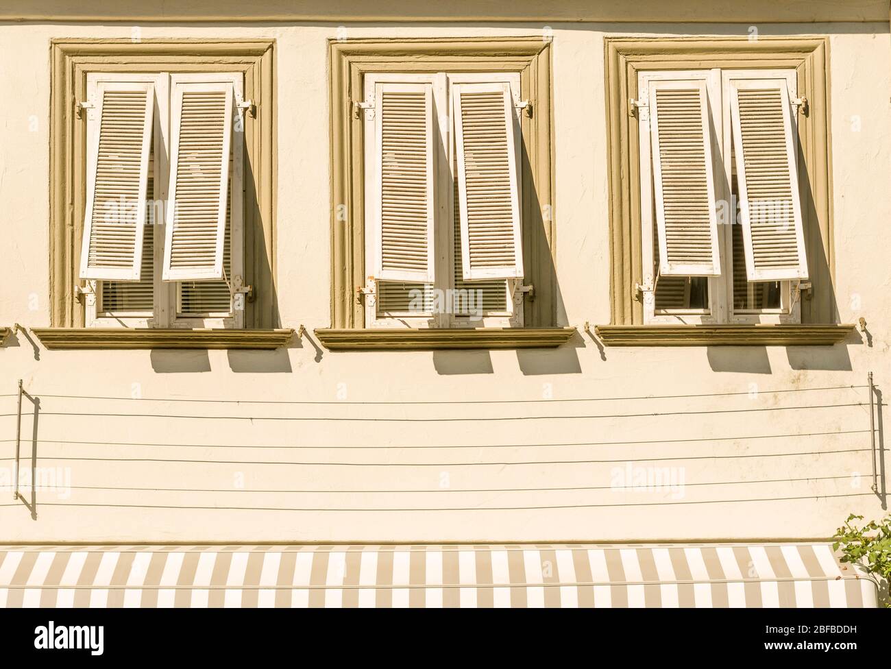 Facciata della casa con stucco 3 finestre e persiane in legno aperto tenda alpinismo aiuti Foto Stock