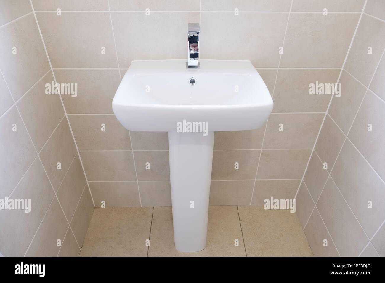 Un lavandino bianco posto accanto ad una parete piastrellata Foto Stock
