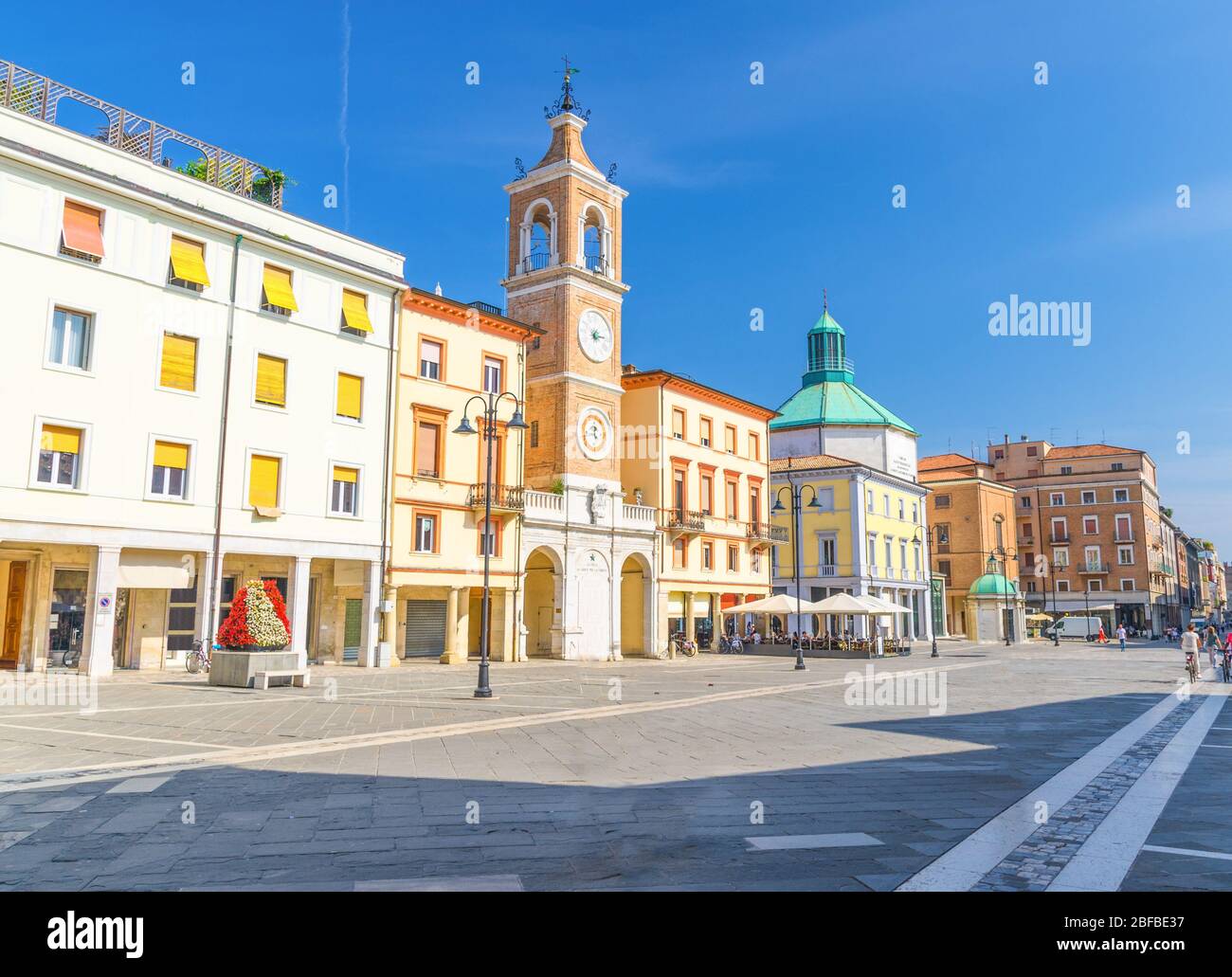 Piazza tre Martiri Piazza tre Martiri con edifici tradizionali con orologio e campanile nel centro storico turistico di Rimini con il blu Foto Stock