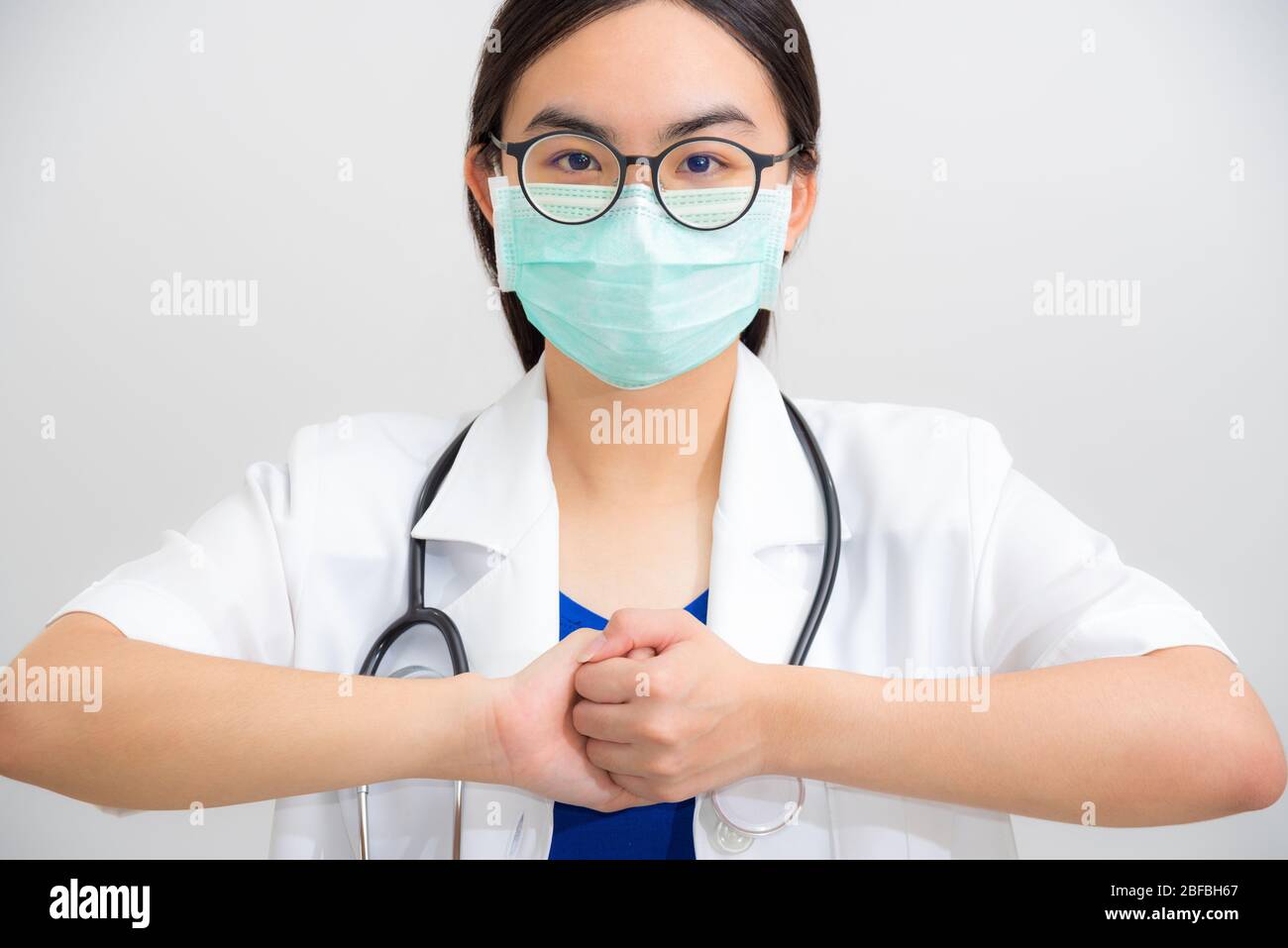 Ritratto bella donna asiatica medico con stetoscopio e maschera per proteggere Corona Virus clasp mano gesto di elemosine per aiutare la cooperazione, lavorare insieme Foto Stock