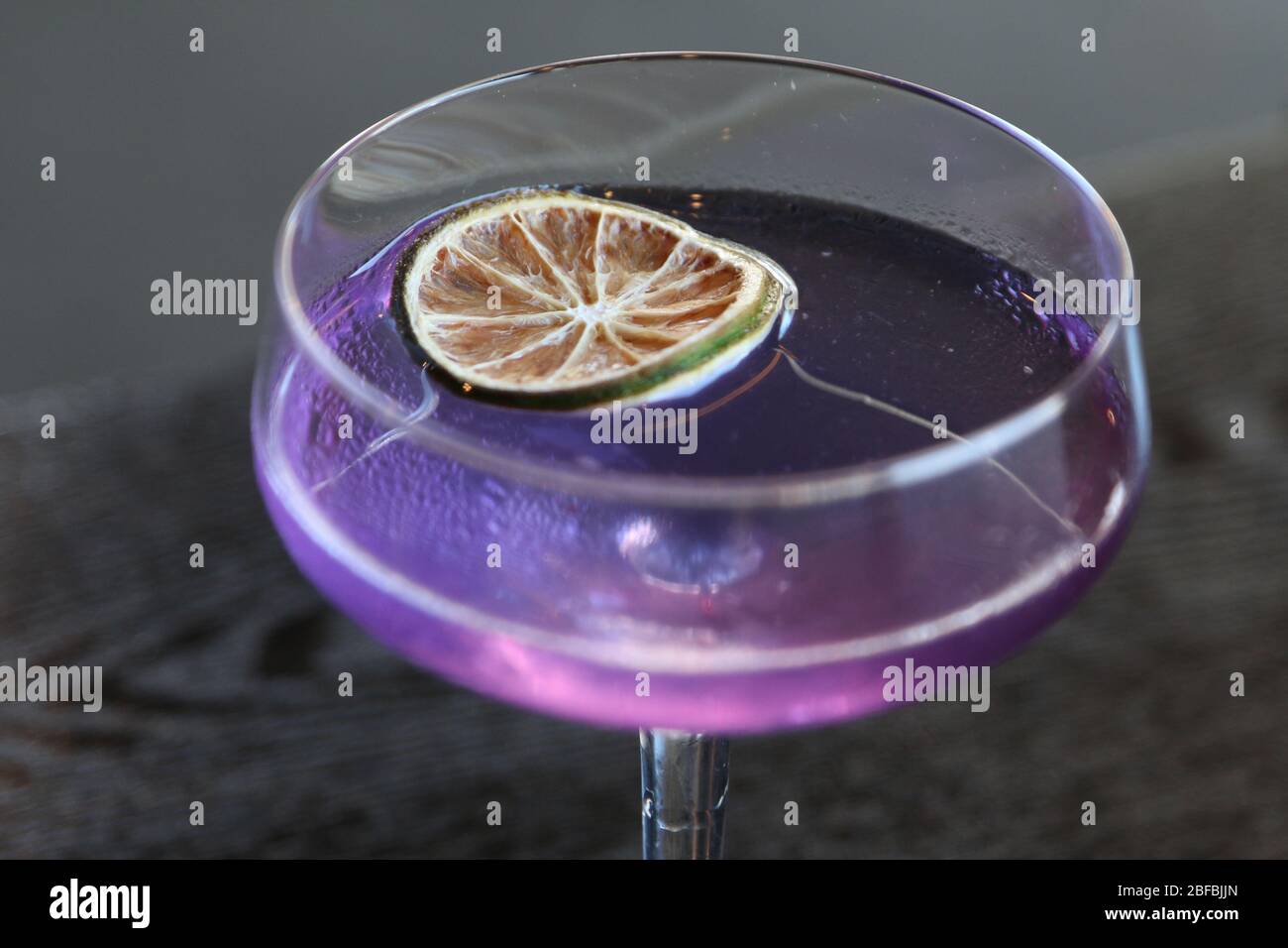 Cocktail viola con ruota di lime Foto Stock