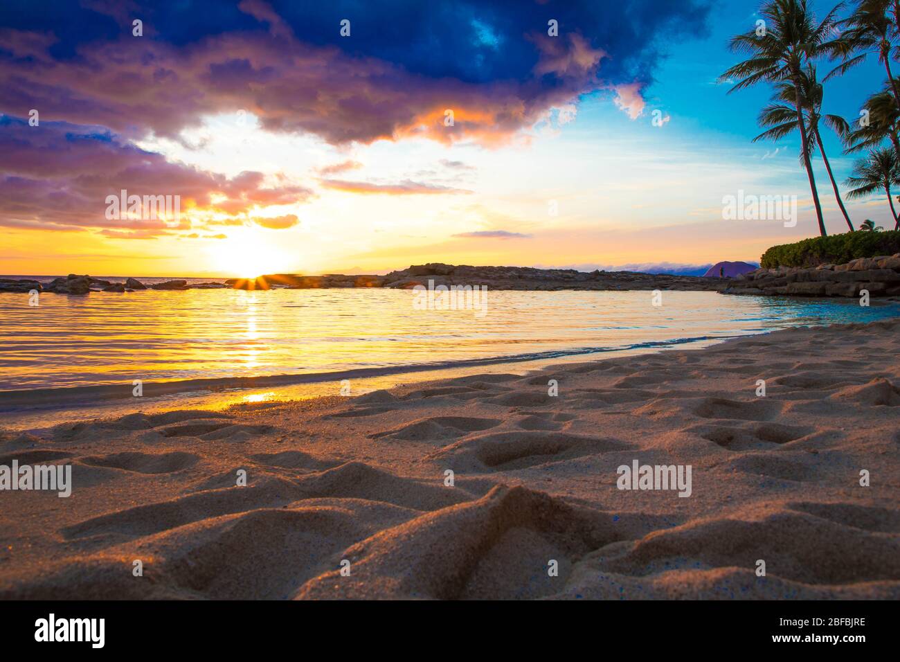 Bellissimo tramonto alle Hawaii da una spiaggia segreta con palme Foto Stock