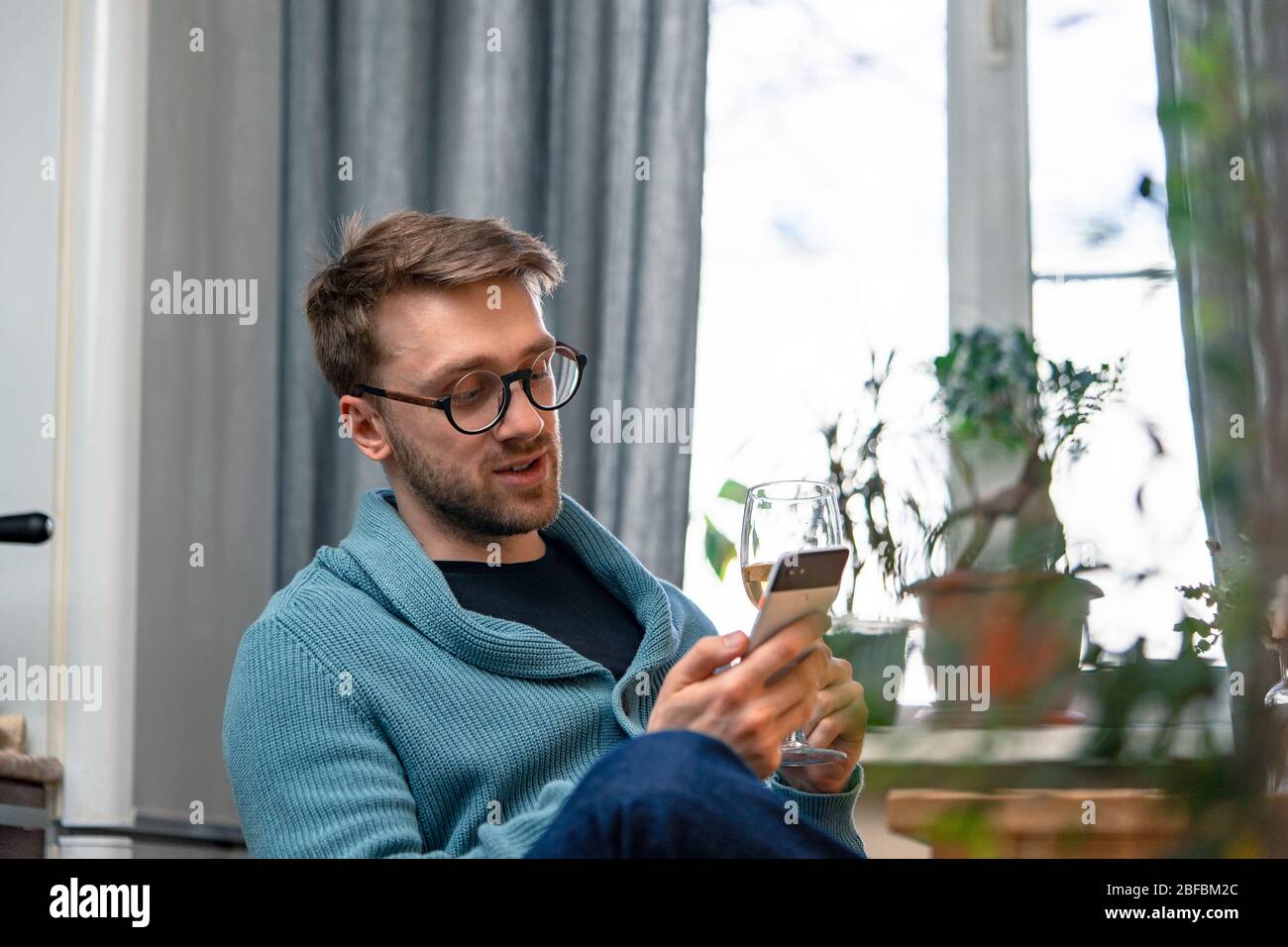 Uomo che chiama i suoi amici da cucina e bere vino con loro tramite Video Chat. Data online, riunione online con gli amici. Rimani a casa. Distanza sociale a Foto Stock