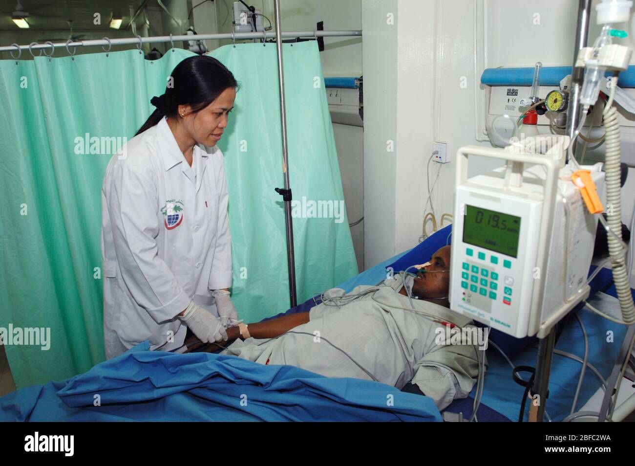 Questo paziente riceve liquidi endovenosi (iv) (nel braccio destro) e ossigeno tramite una cannula nasale. Indossa un ossimetro a impulsi sul suo indice fi destro Foto Stock